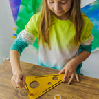 A young maker focused on decorating the wooden cheese, practicing patience and attention to detail.