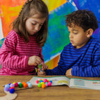 Creative details: kids gluing soft pompoms onto the caterpillar's back and shiny star stickers onto the disco roller skates.