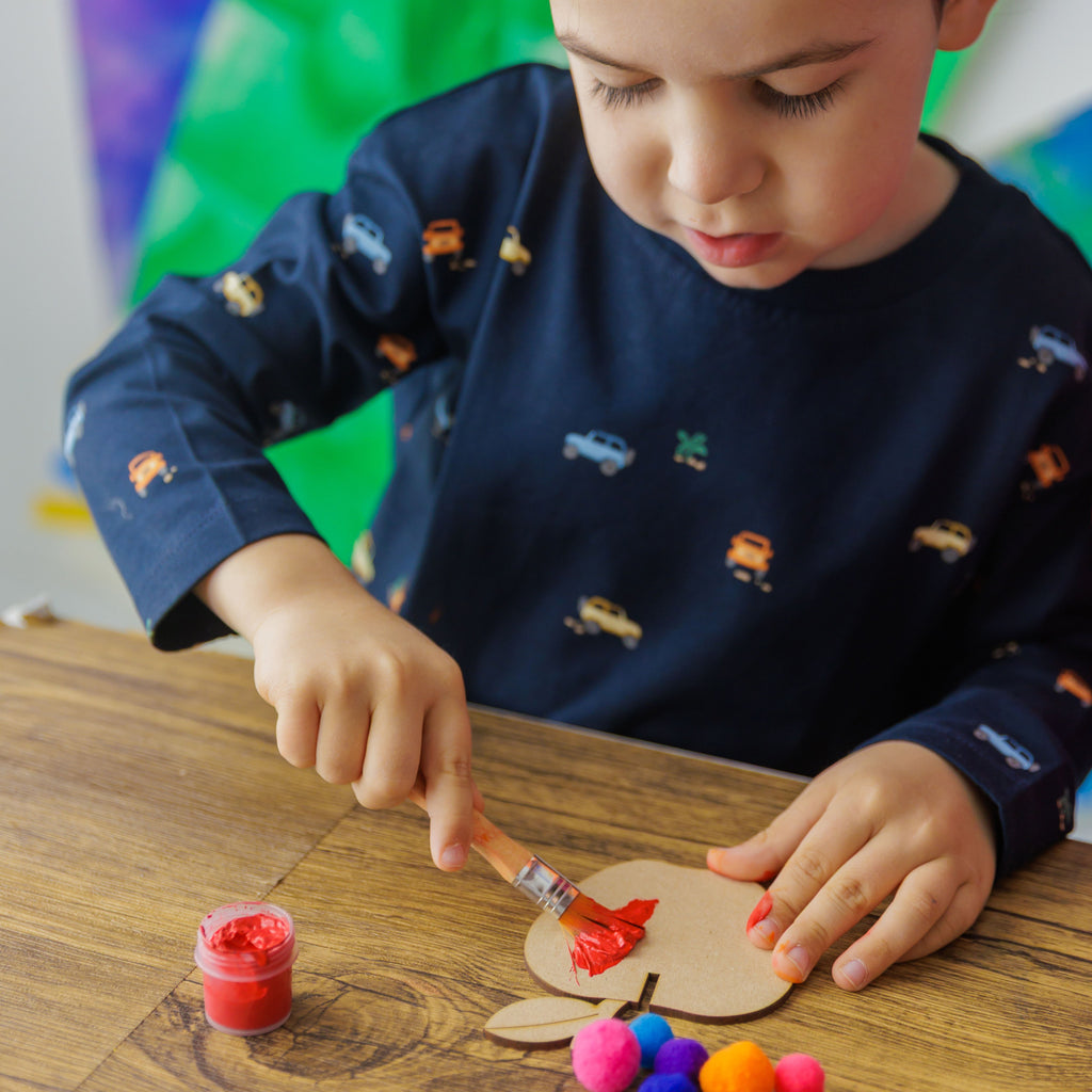 A child giving the wooden apple cheerful disco colors using the included paint set and brush.