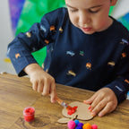 A child giving the wooden apple cheerful disco colors using the included paint set and brush.