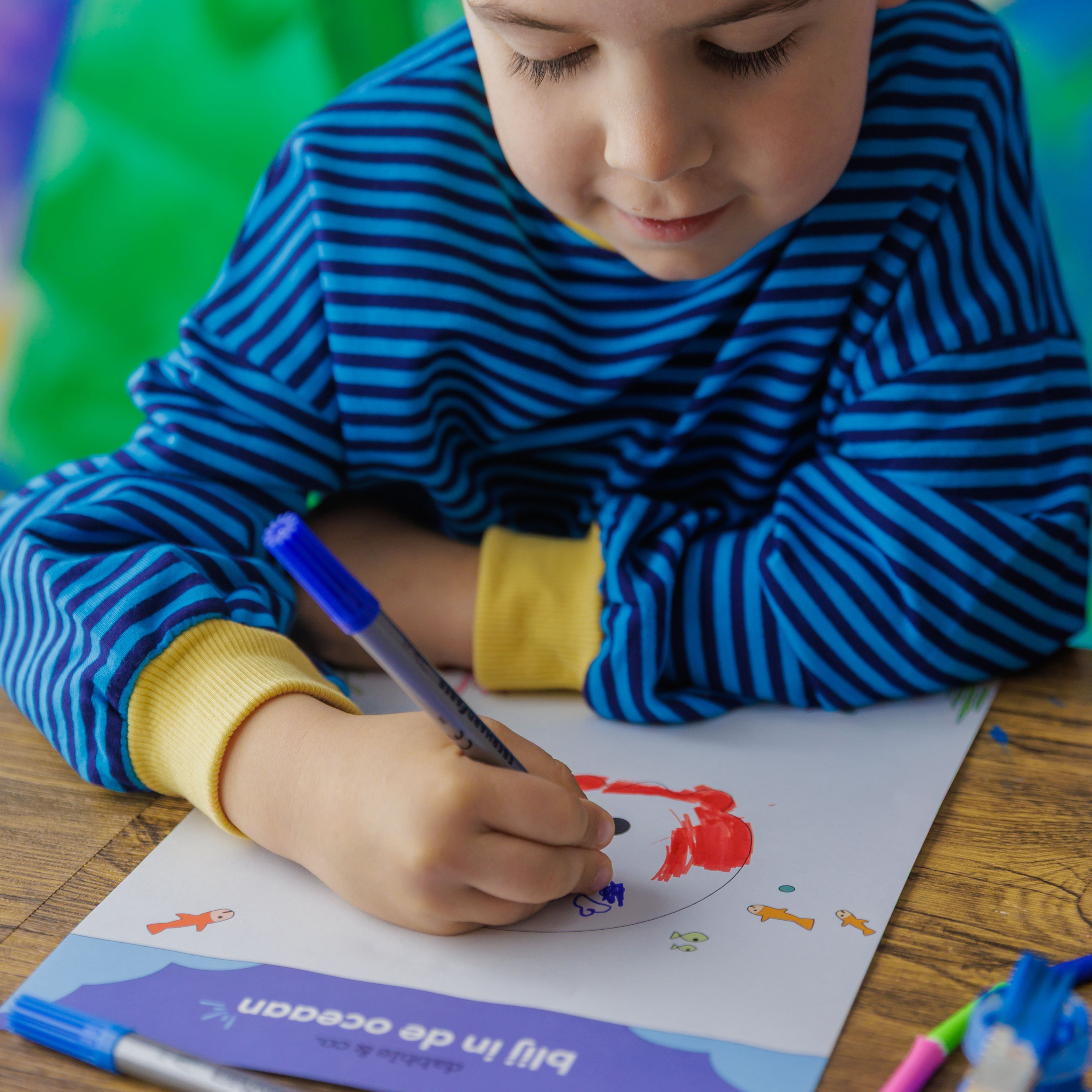 Extra fun: a child coloring the Jelly! the Jellyfish coloring sheet while the paint on the wooden project dries.