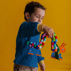 A proud child showing off their finished Disco Caterpillar, complete with pompoms and glittering stars on the wheels.