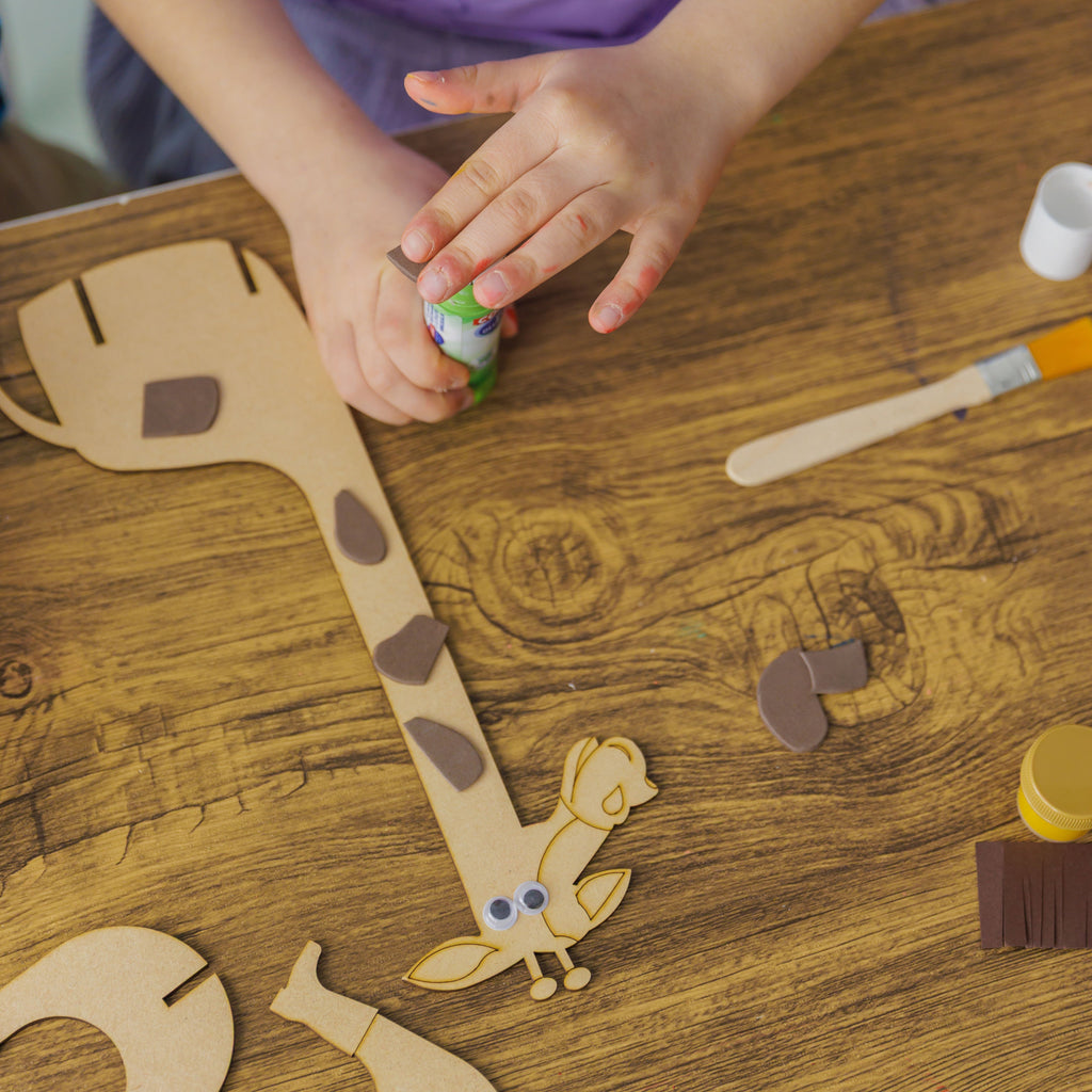 Hands-on crafting: a young maker assembling the Happy Giraffe by attaching textured foam details.
