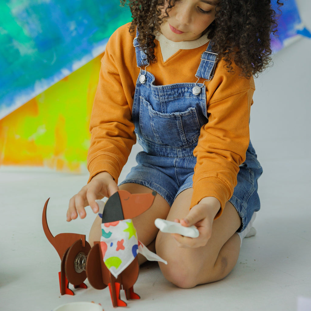 A happy child showing off their handmade wooden dog friend, a result of an afternoon of screen-free fun.