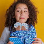roud maker showing their personalized handmade ocean decoration: a painted wooden whale with sparkles.