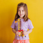 A proud child holding their completed Happy Giraffe; a colorful wooden craft project featuring 3D foam dots and cardboard manes.