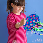 A girl playing with her finished Jelly! the Jellyfish lantern on a stick; the tentacles dance joyfully in the air.