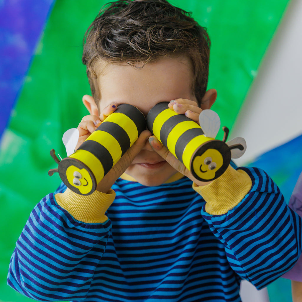 Creative play with the Bee Hotel kit: child looking through cardboard tube bees like binoculars.
