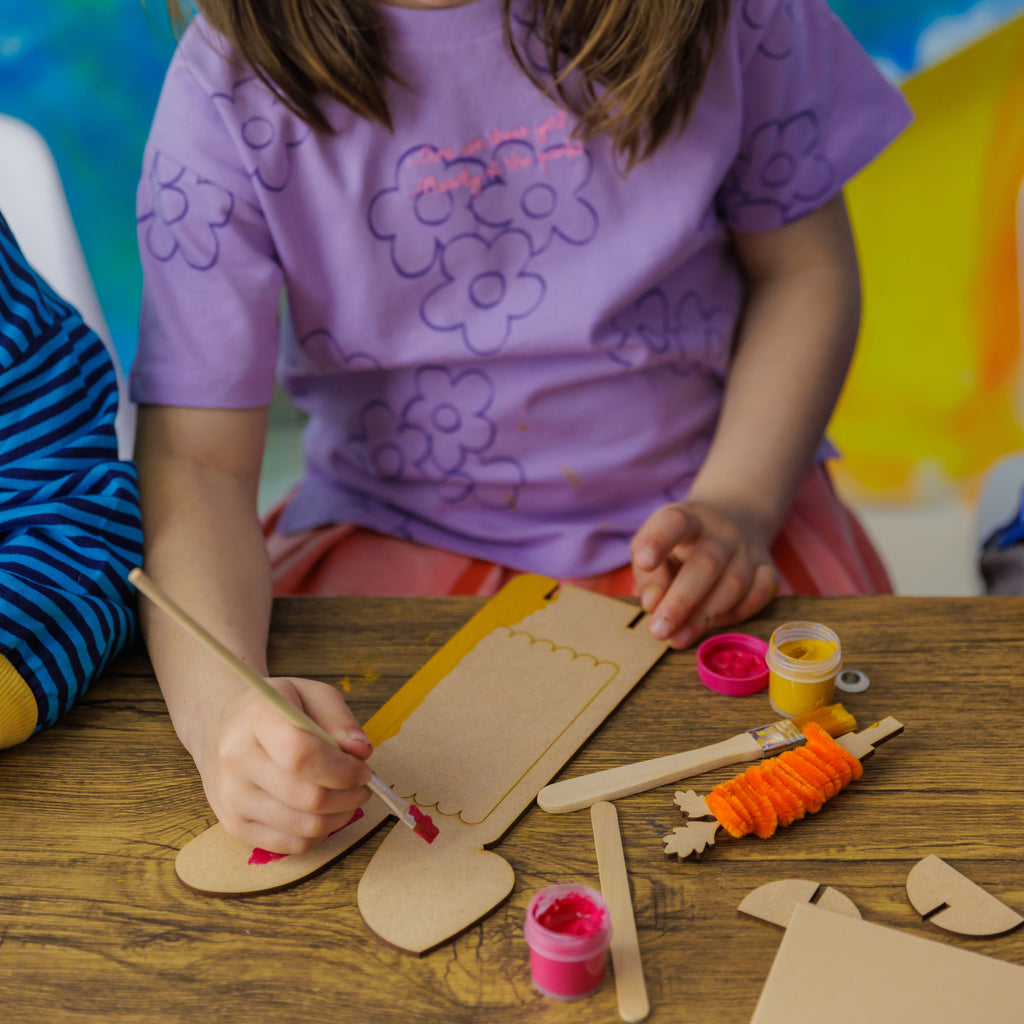 A child painting the wooden popsicle sticks from the Bunny and the Carrot Patch set to create a unique and colorful bunny.