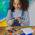 Cutting and gluing glitter paper to personalize Robbie the Robot with unique patterns and shapes.