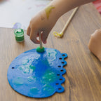 Creative techniques for kids: using sponge brushes to stamp textures and patterns onto the painted wooden jellyfish.