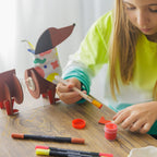 A child using a paintbrush to add bright colors to the boots of Dot the Dog.